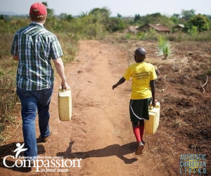 Compassion international with a Uganda child, collecting water